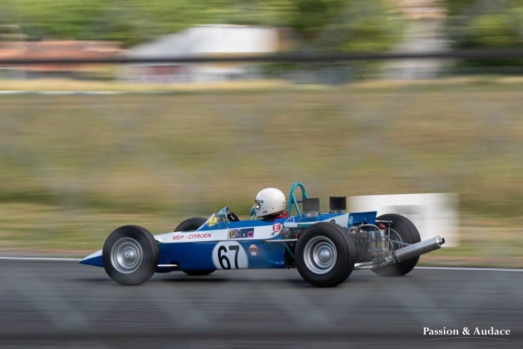 Pilote de monoplace en pleine course sur le circuit d'Albi vu derrière un grillage