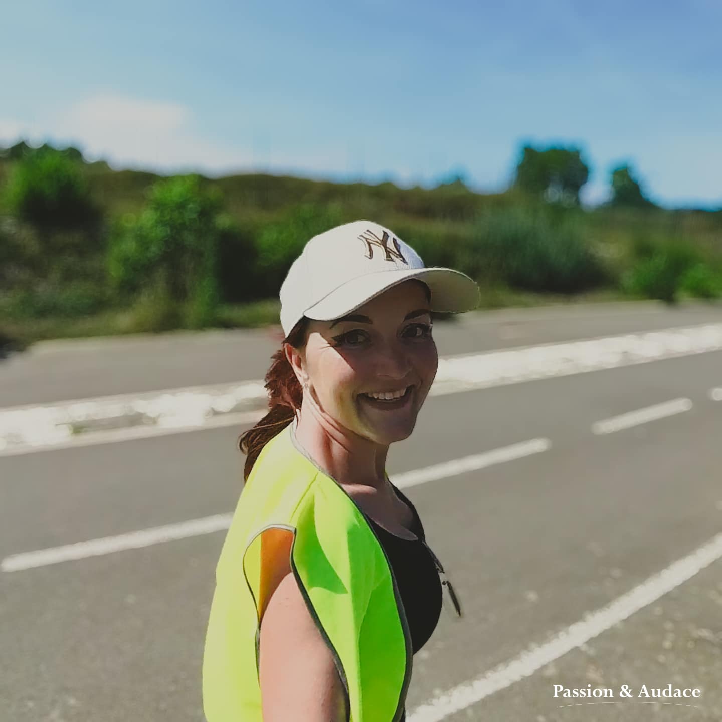 Jeune femme avec une casquette et un gilet jaune regardant vers l'objectif en souriant