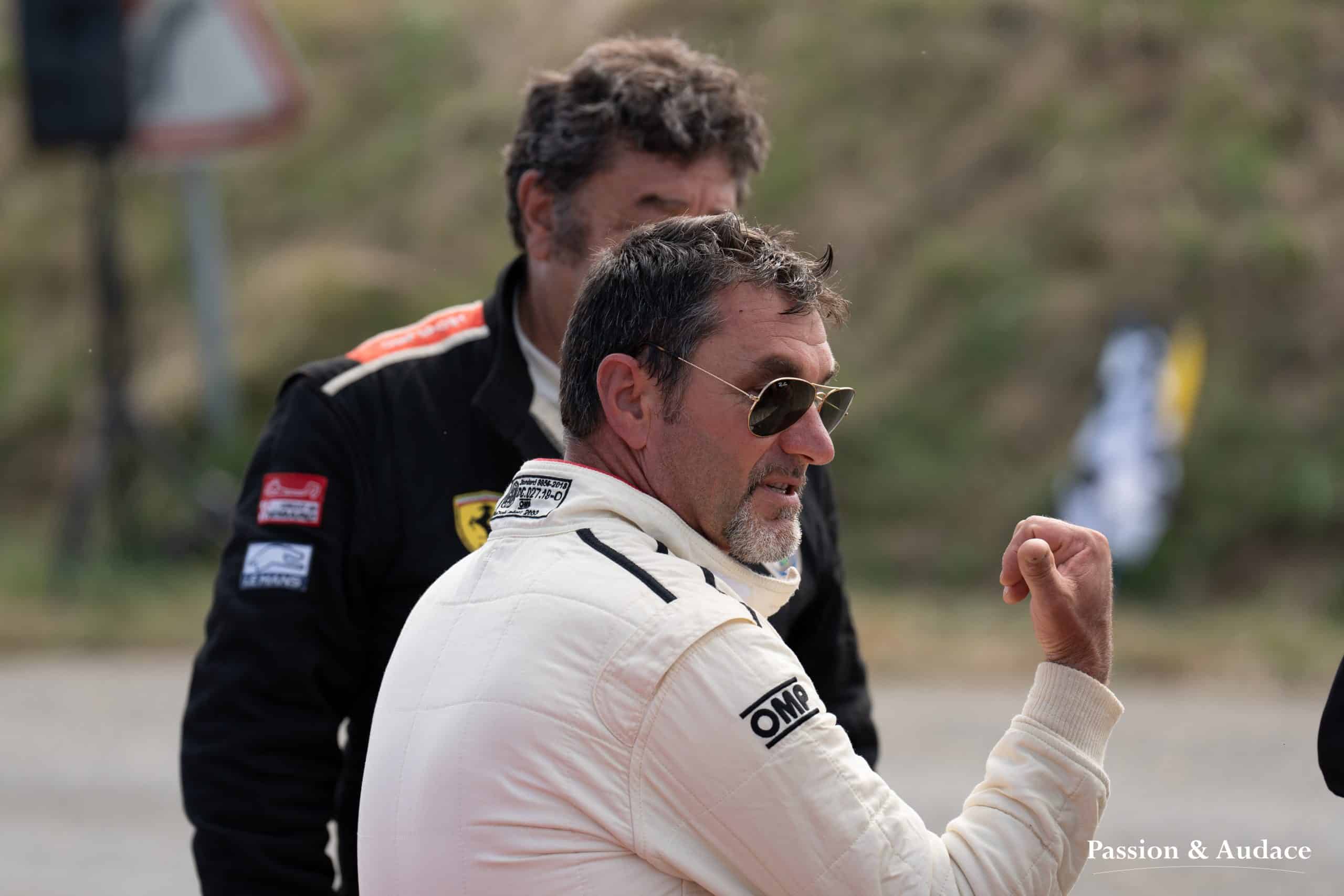 Photographie de deux hommes en tenue de pilote auto en train d'échanger sur leur performance sportive