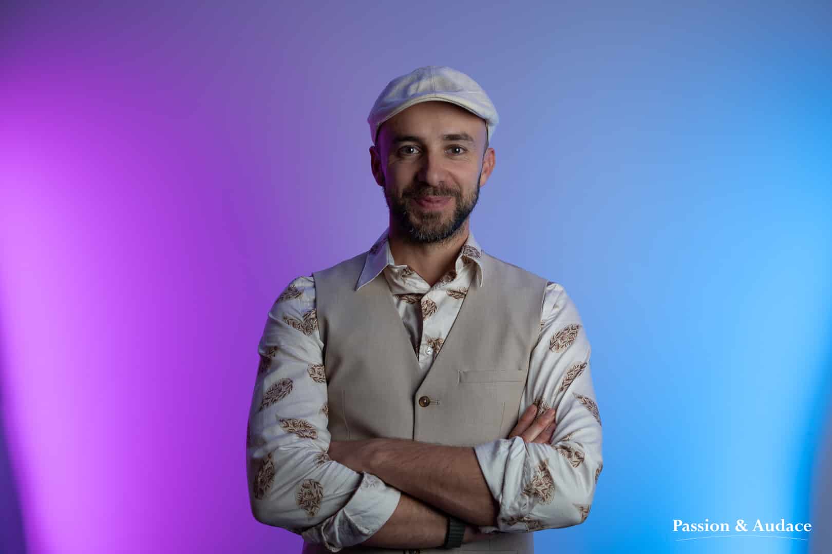 Photo portrait d'un professionnel souriant en tenue rétro avec une chemise et un gilet de costume beige avec une casquette béret beige et un fond de lumières bleu violet
