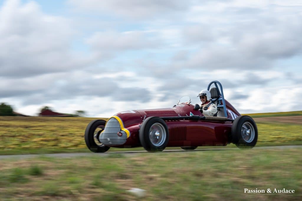 Photographie d'un véhicule rouge bordeaux faisant la course sur le circuit de Cadours Laréole avec un effet de vitesse.