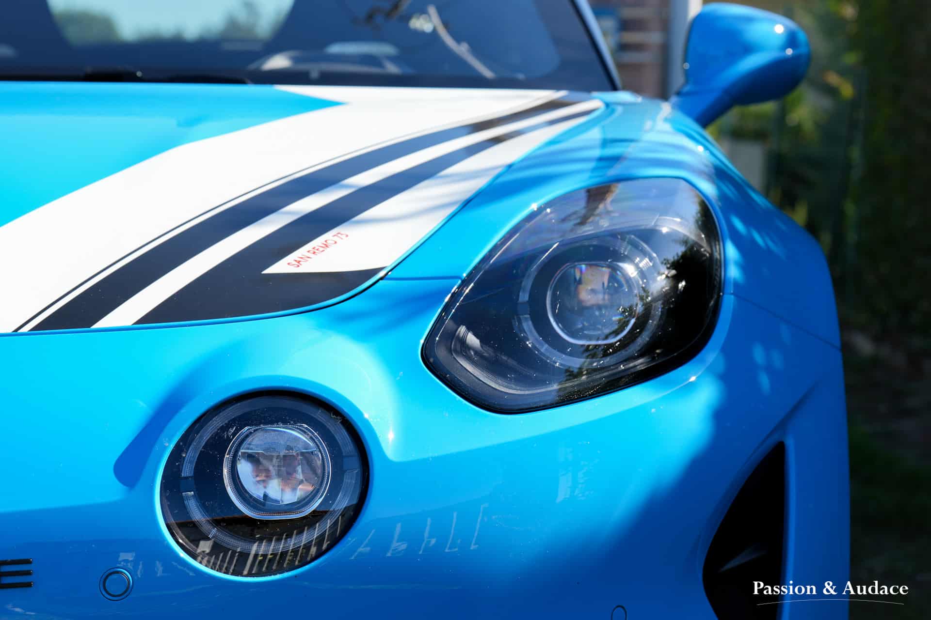 Photographie gros plan du feu avant d'une Alpine A110 de couleur bleu