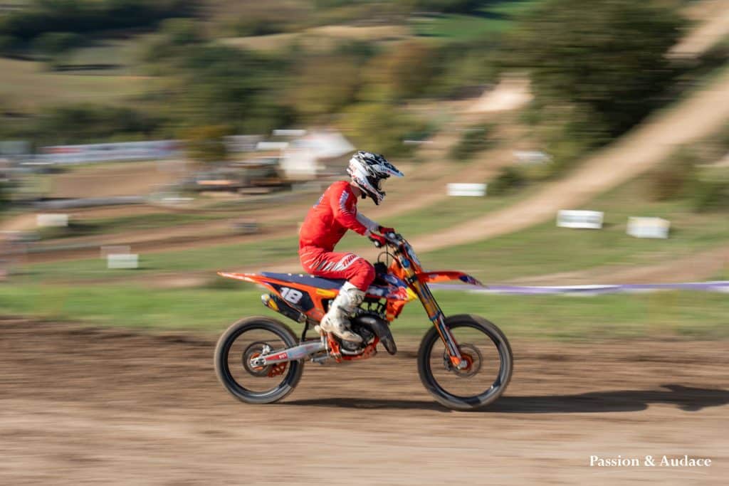 Photographie d'un pilote de cross en plein parcours avec un effet de filé de vitesse