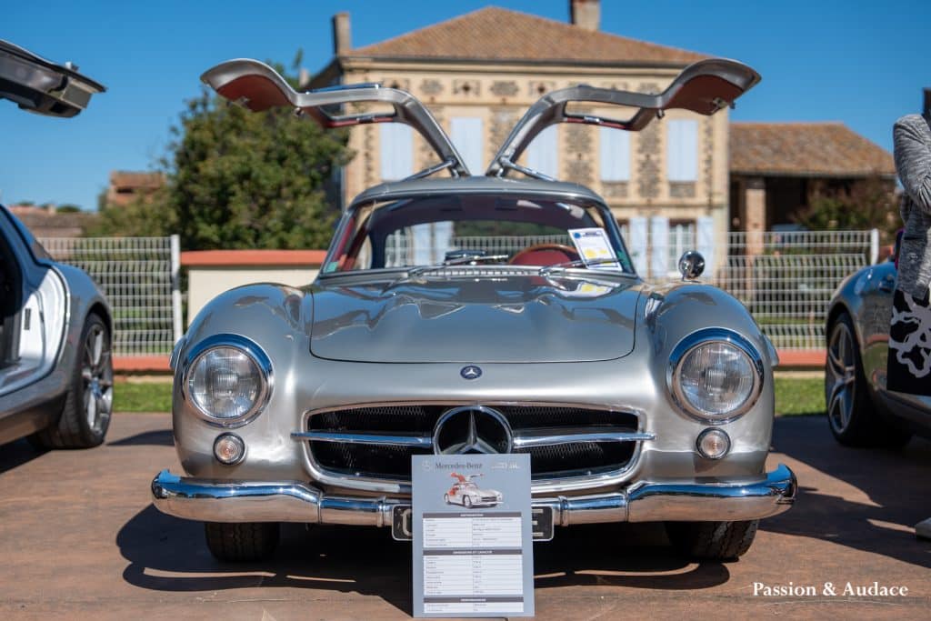 Photographie d'une Mercedes 300SL grise les portes papillon en l'air. Photo de face.