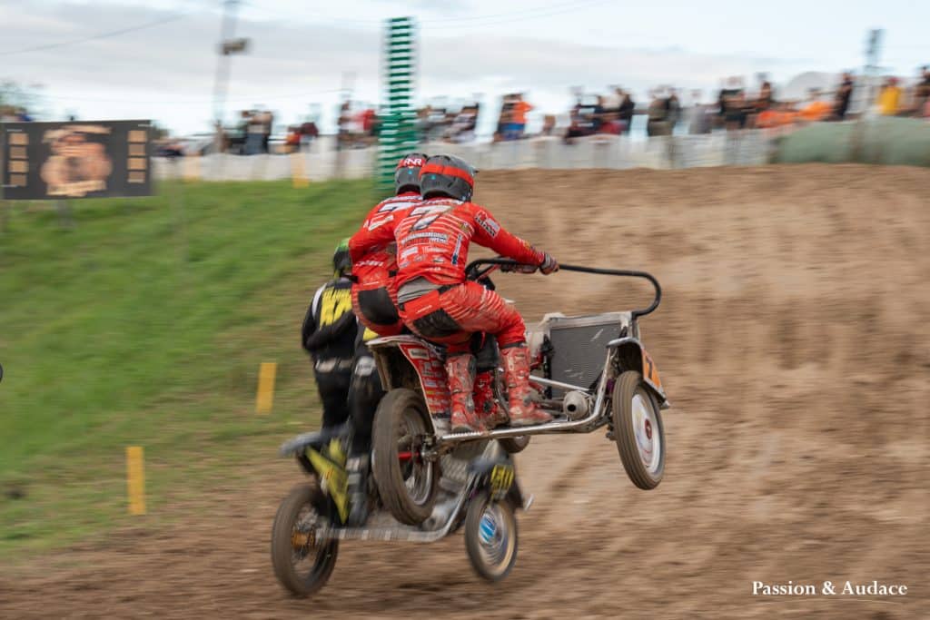 Photographie d'un copilote de sidecar cross tenant le pilote par la taille en plein vol