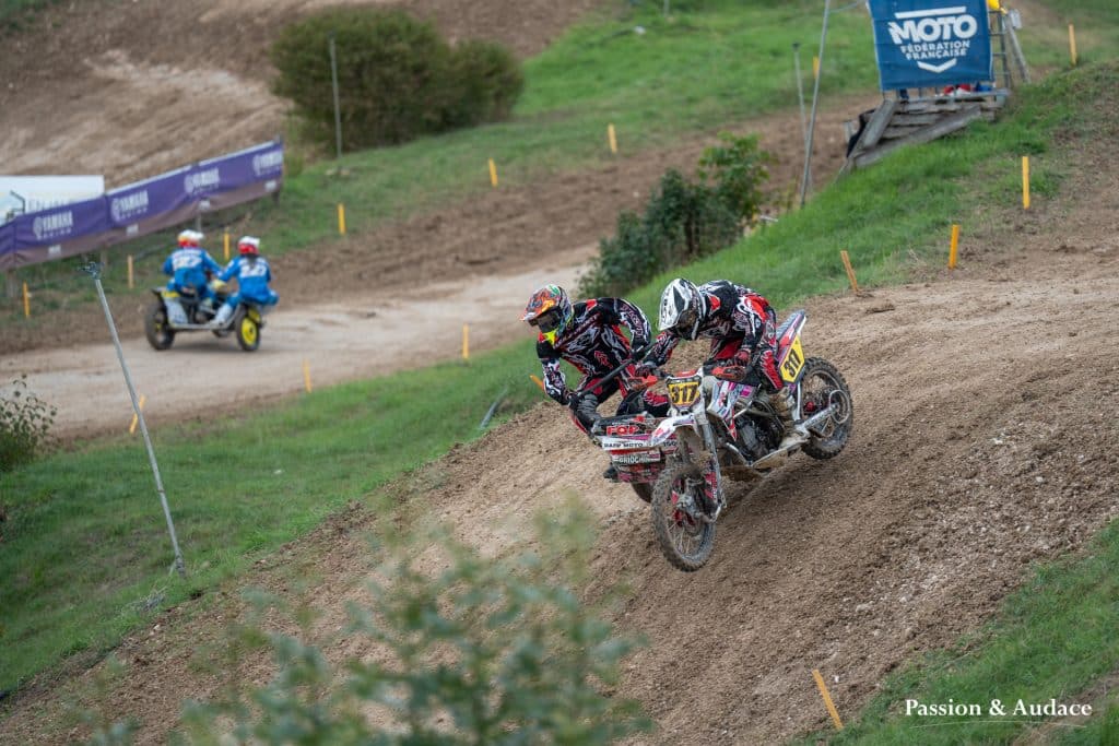Photographie d'un pilote de sidecar cross avec son copilote en pleine course avec un effet de filé de vitesse en train dévaler une bute de terre