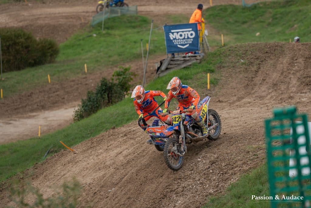 Photographie d'un pilote de sidecar cross avec son copilote en pleine course en train de dévaler une pente
