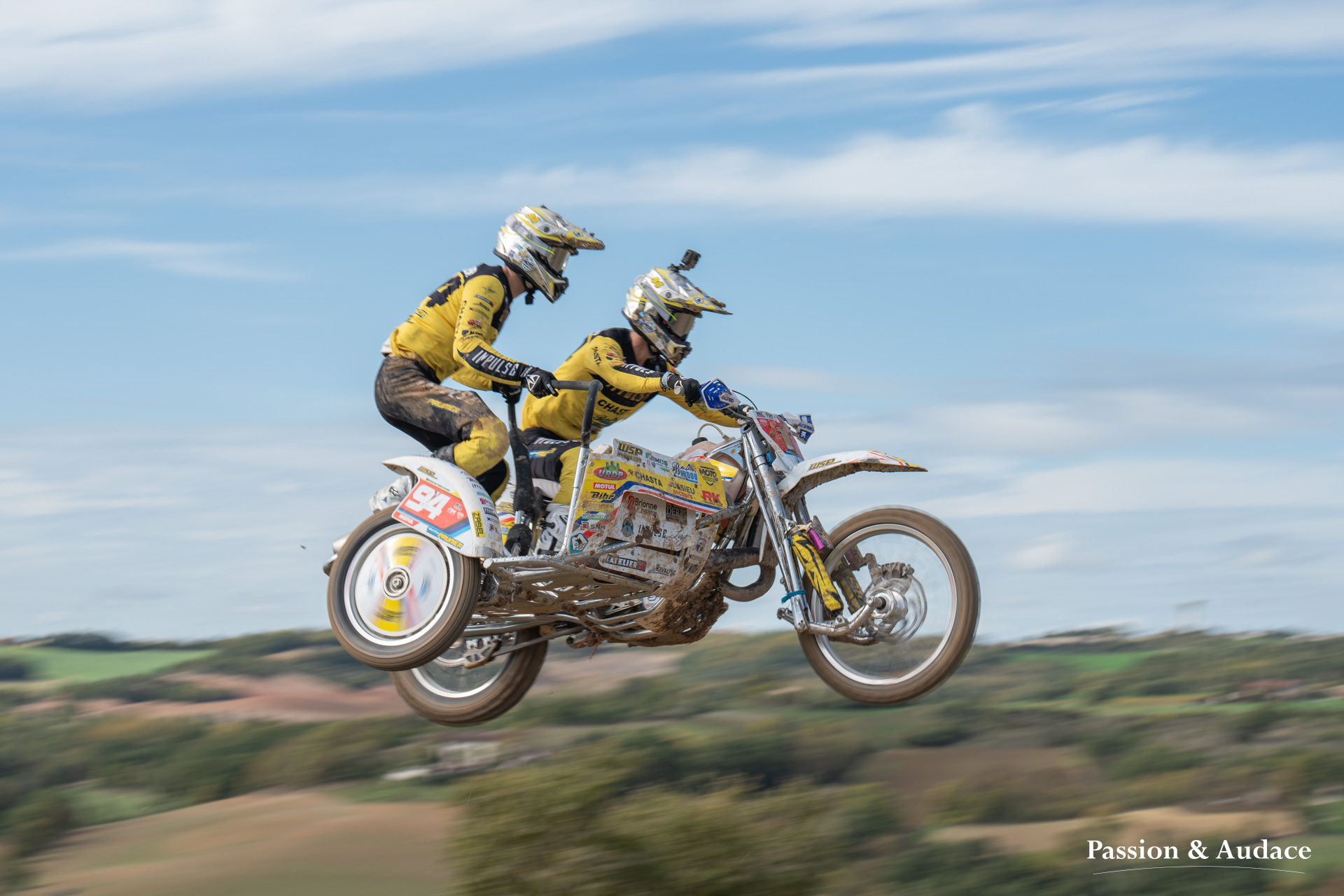 Photographie d'un pilote et copilote de sidecar cross en plein vol dans les airs